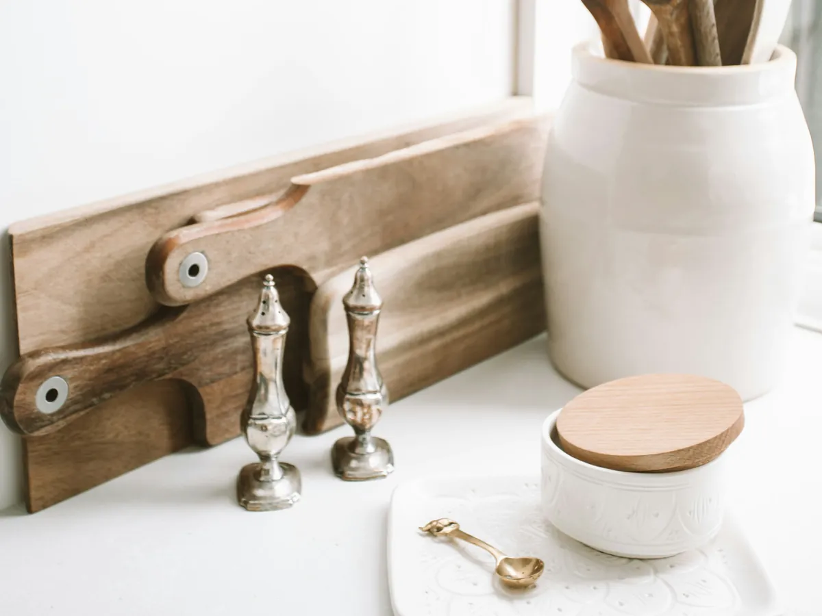 Wooden spoons in a ceramic jar beside cutting boards